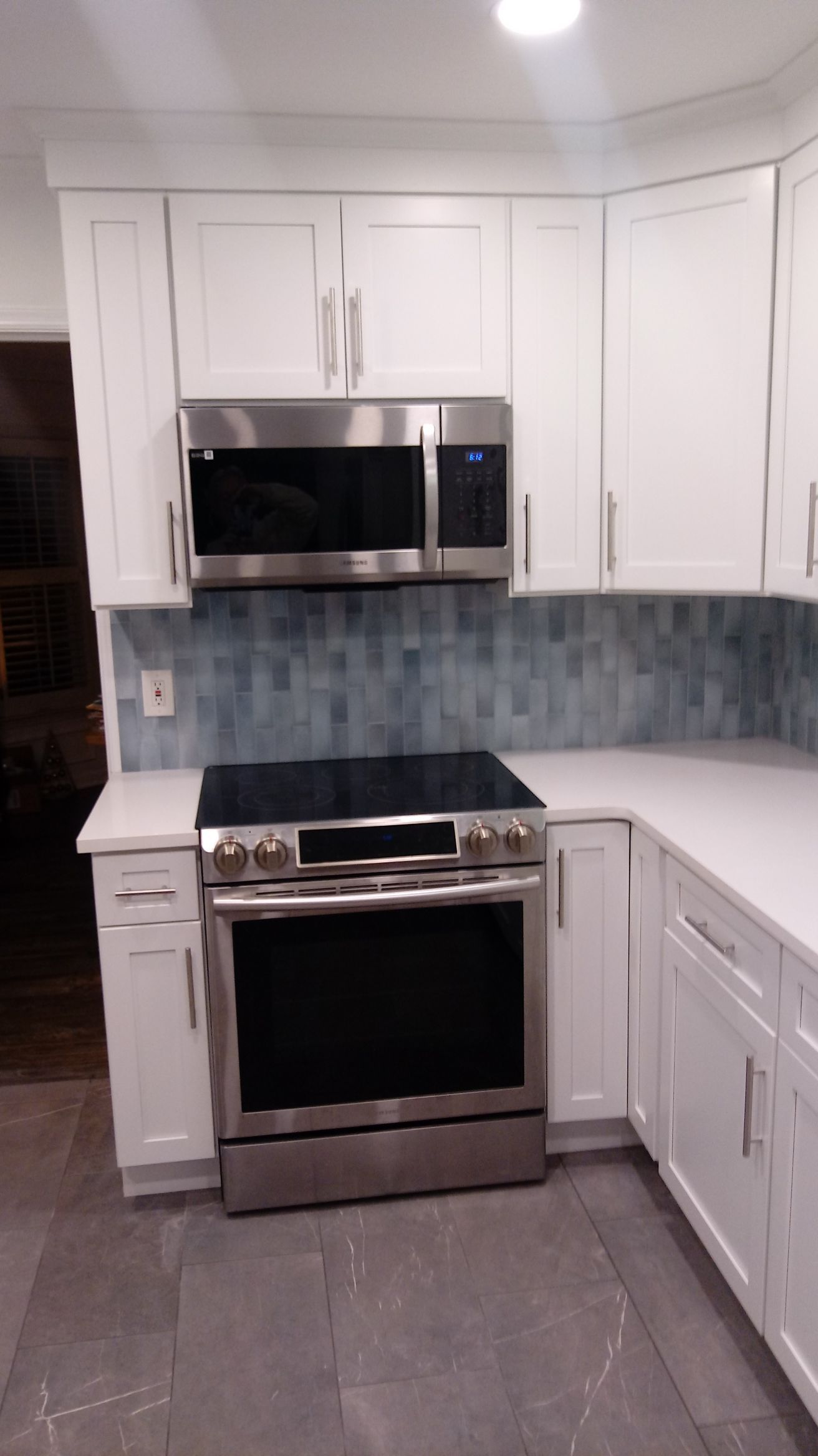 White kitchen cabinets with stainless steel appliances and blue tile backsplash.