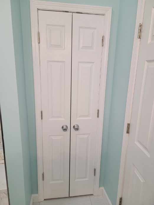 White bi-fold closet doors in a light blue painted hallway.
