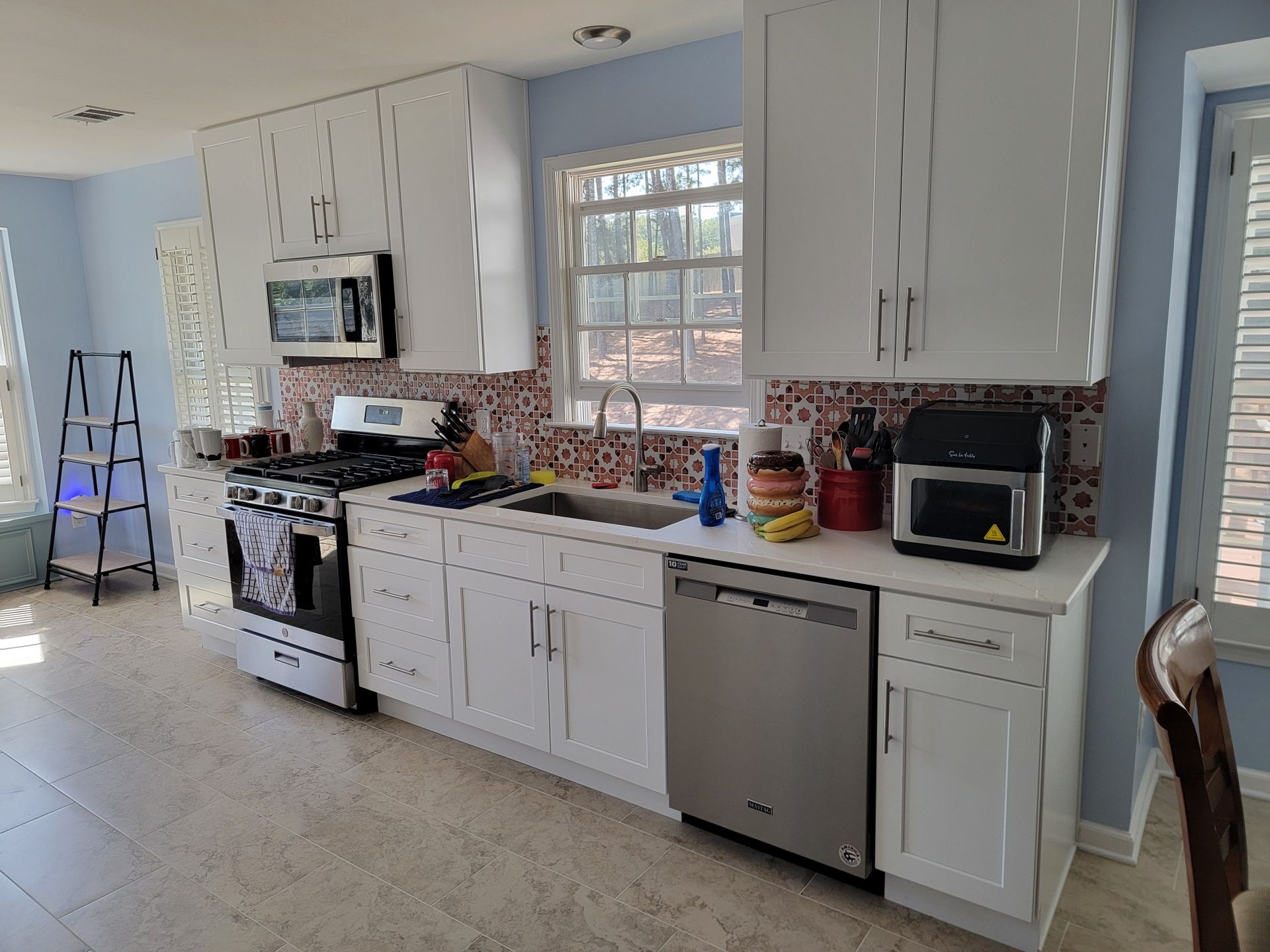 White kitchen with stainless steel appliances, white cabinets, and blue walls.