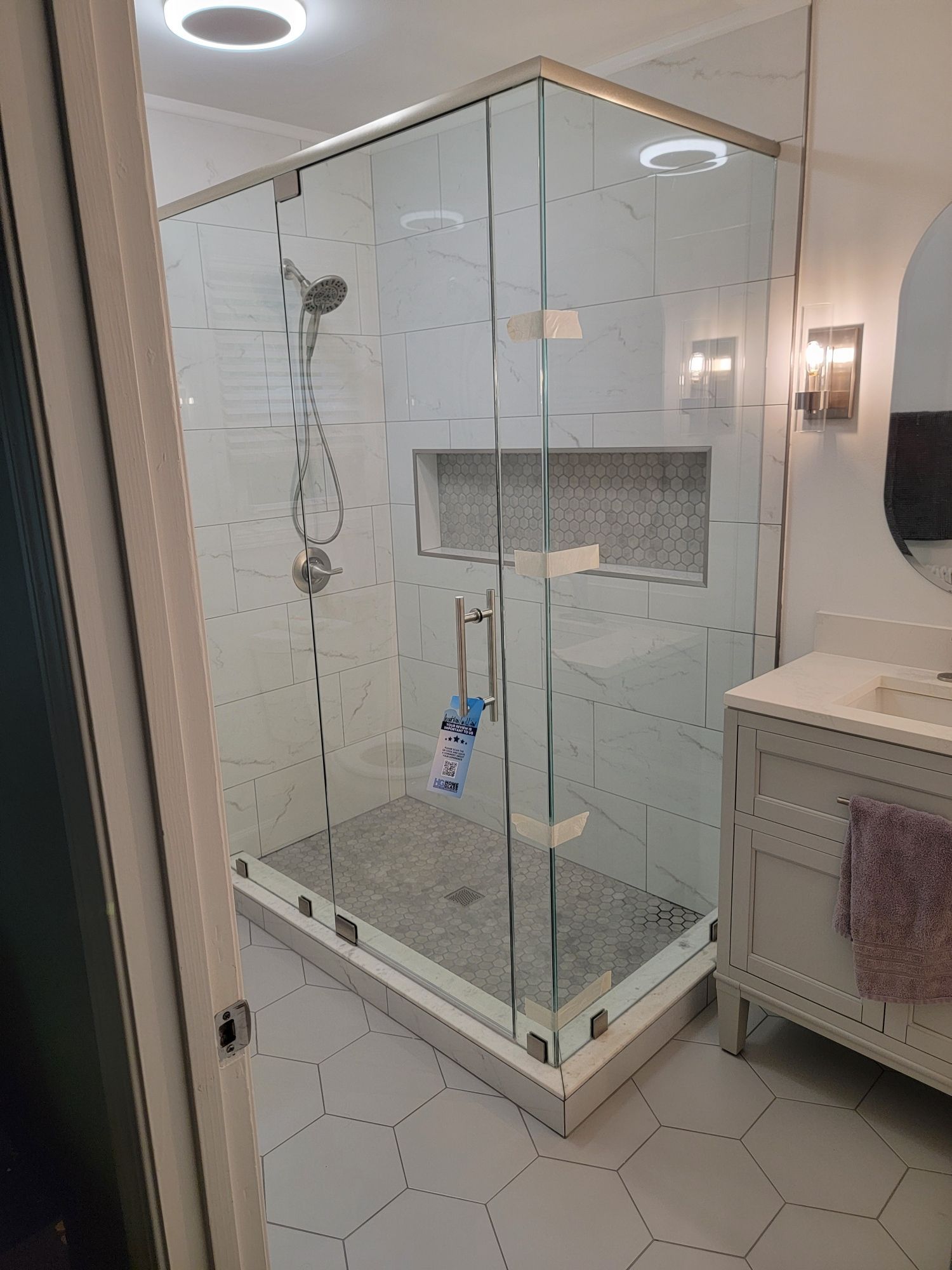 Glass shower with white tile walls and hexagonal floor tiles.