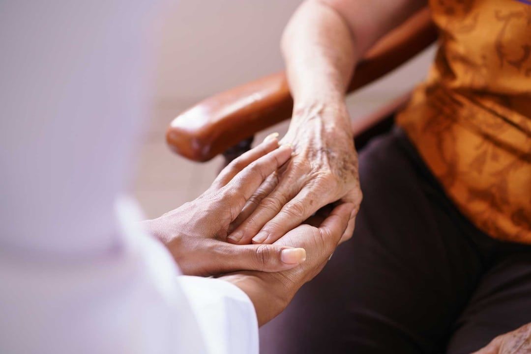 A person is holding another person 's hand while sitting in a chair.