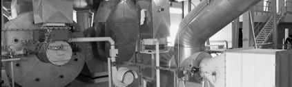 Ein Schwarzweißfoto einer Fabrik mit vielen Rohren und Maschinen.