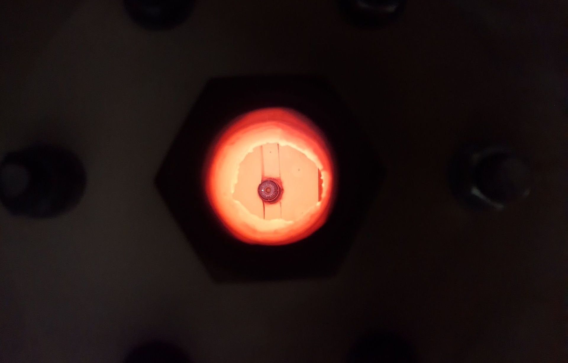 A glowing furnace interior, seen through a hexagon opening, with a small object inside.