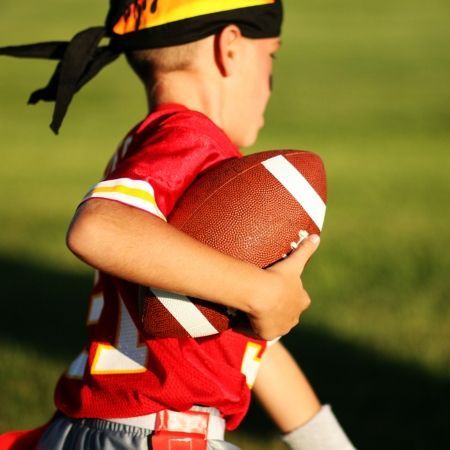 Youth athlete practicing flag football drills with a football during training