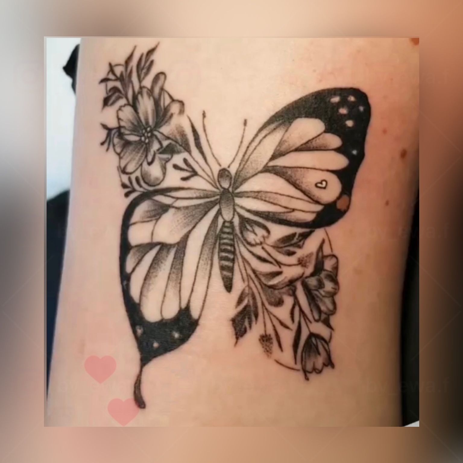 Ein schwarz-weißes Tattoo eines Schmetterlings mit Blumen