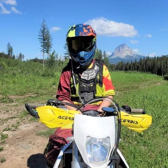 Ashley, an EVR employee, wearing a helmet sitting on an off road bike in the Rocky Mountains. 
