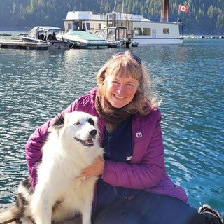 Bronwen, an EVR employee, sitting with her dog beside a lake.