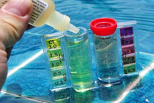 A person is pouring a bottle of liquid into a test tube.
