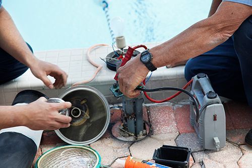 Two men are working on a swimming pool pump.