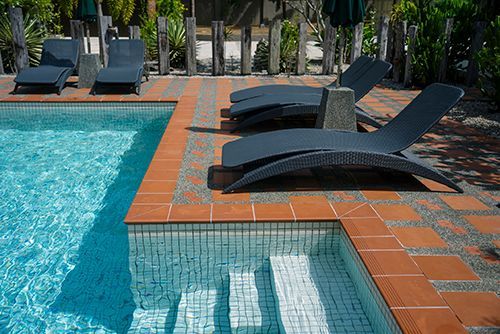 A swimming pool with chairs and umbrellas around it A swimming pool with chairs and umbrellas around it