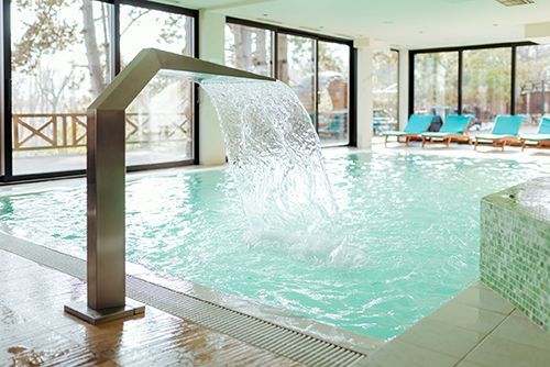 There is a waterfall in the middle of a swimming pool. There is a waterfall in the middle of a swimming pool.