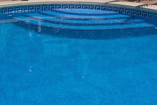 A swimming pool with blue tiles and stairs in it. A swimming pool with blue tiles and stairs in it.