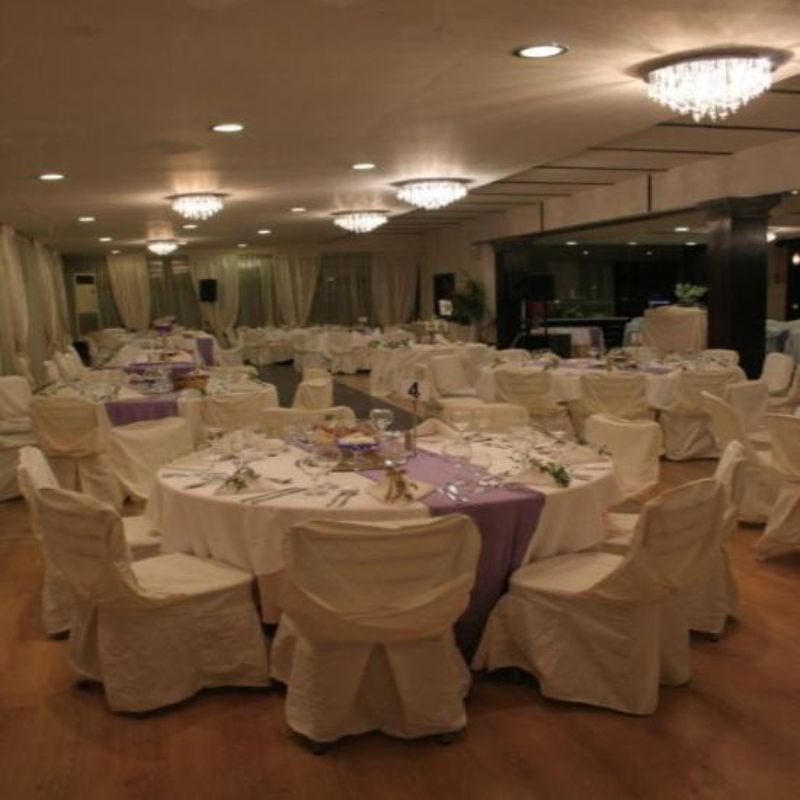 A large room with tables and chairs set up for a wedding reception