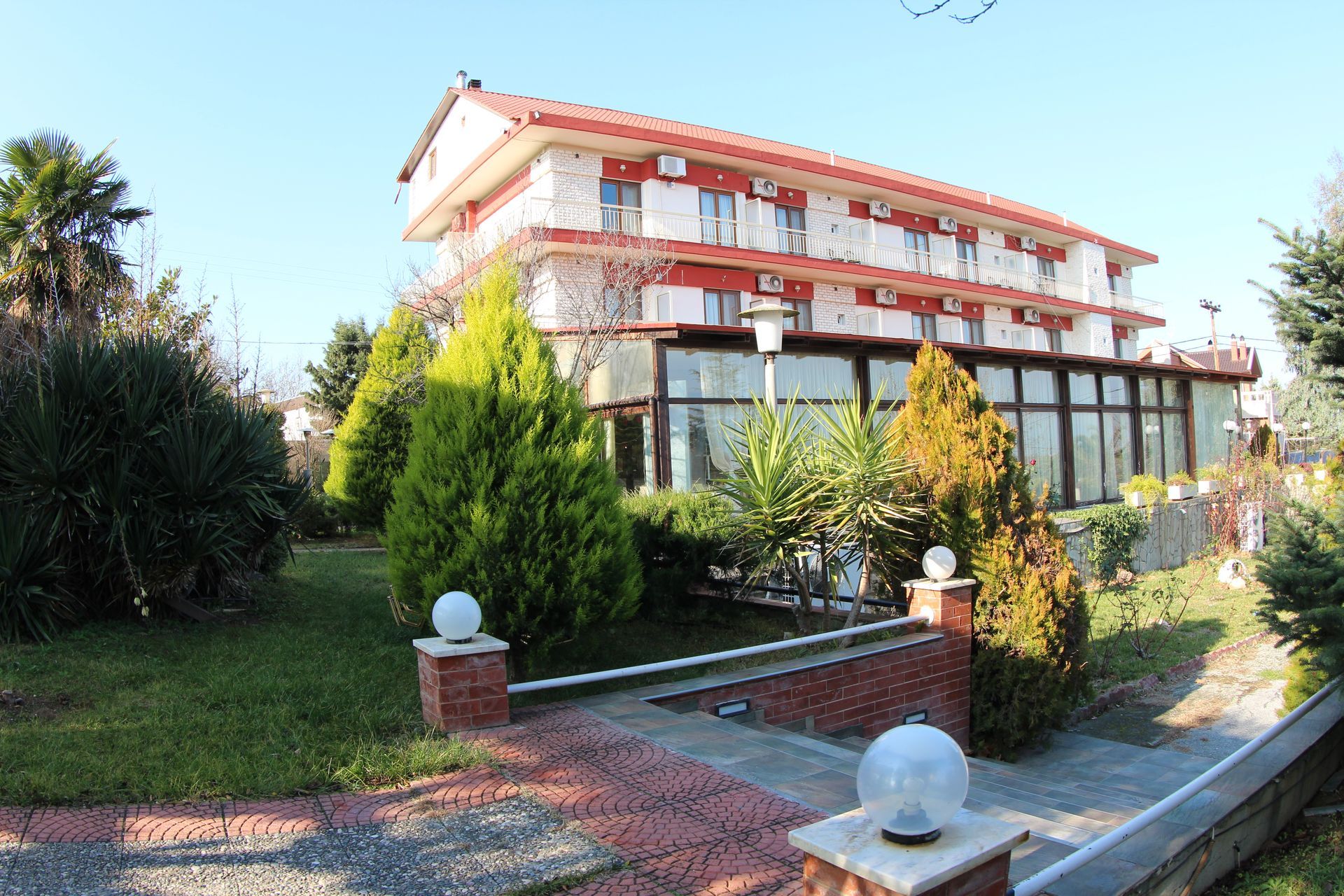 A large building with a lot of windows is surrounded by trees and bushes.