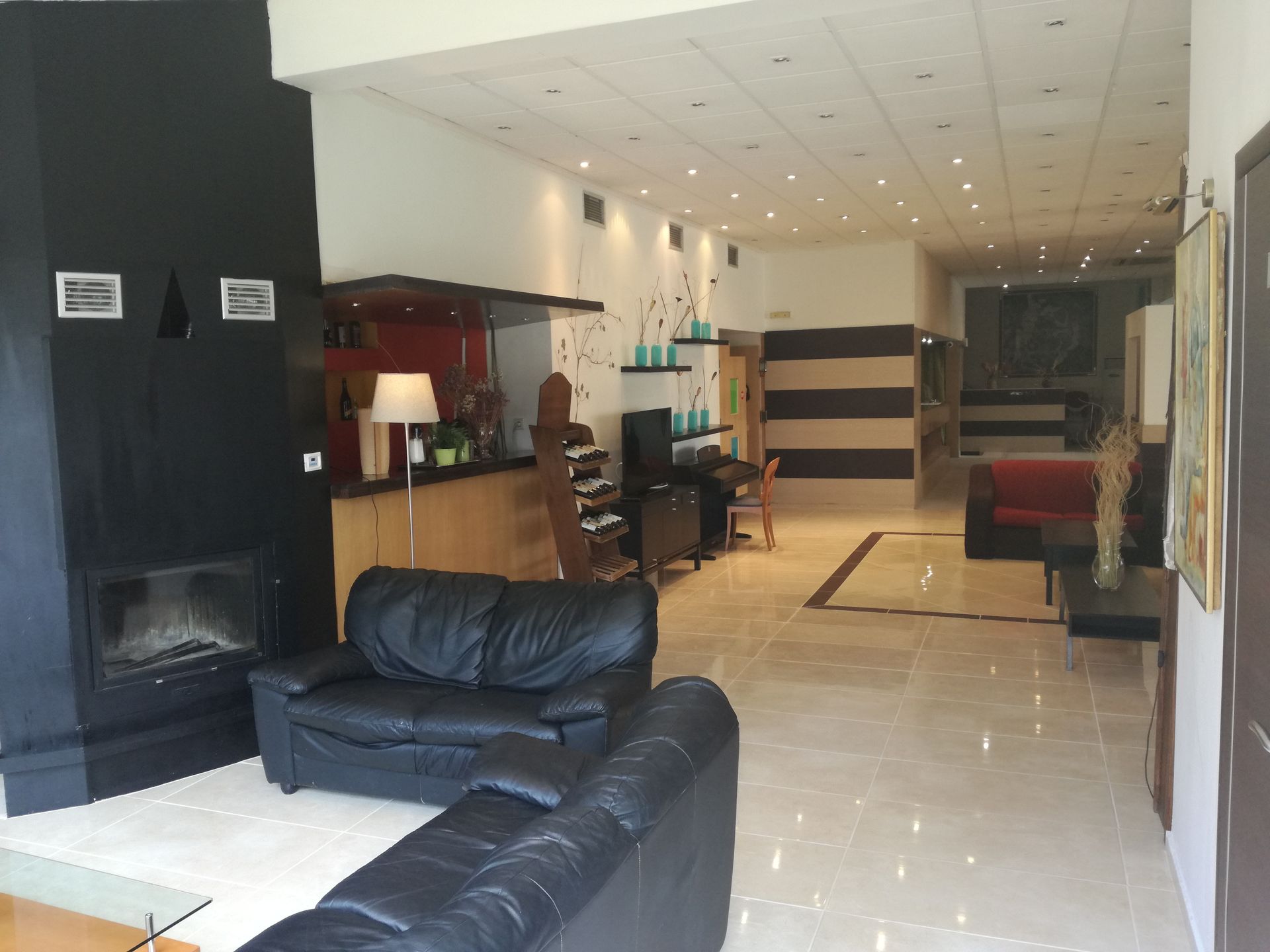 A living room with black leather couches and a fireplace