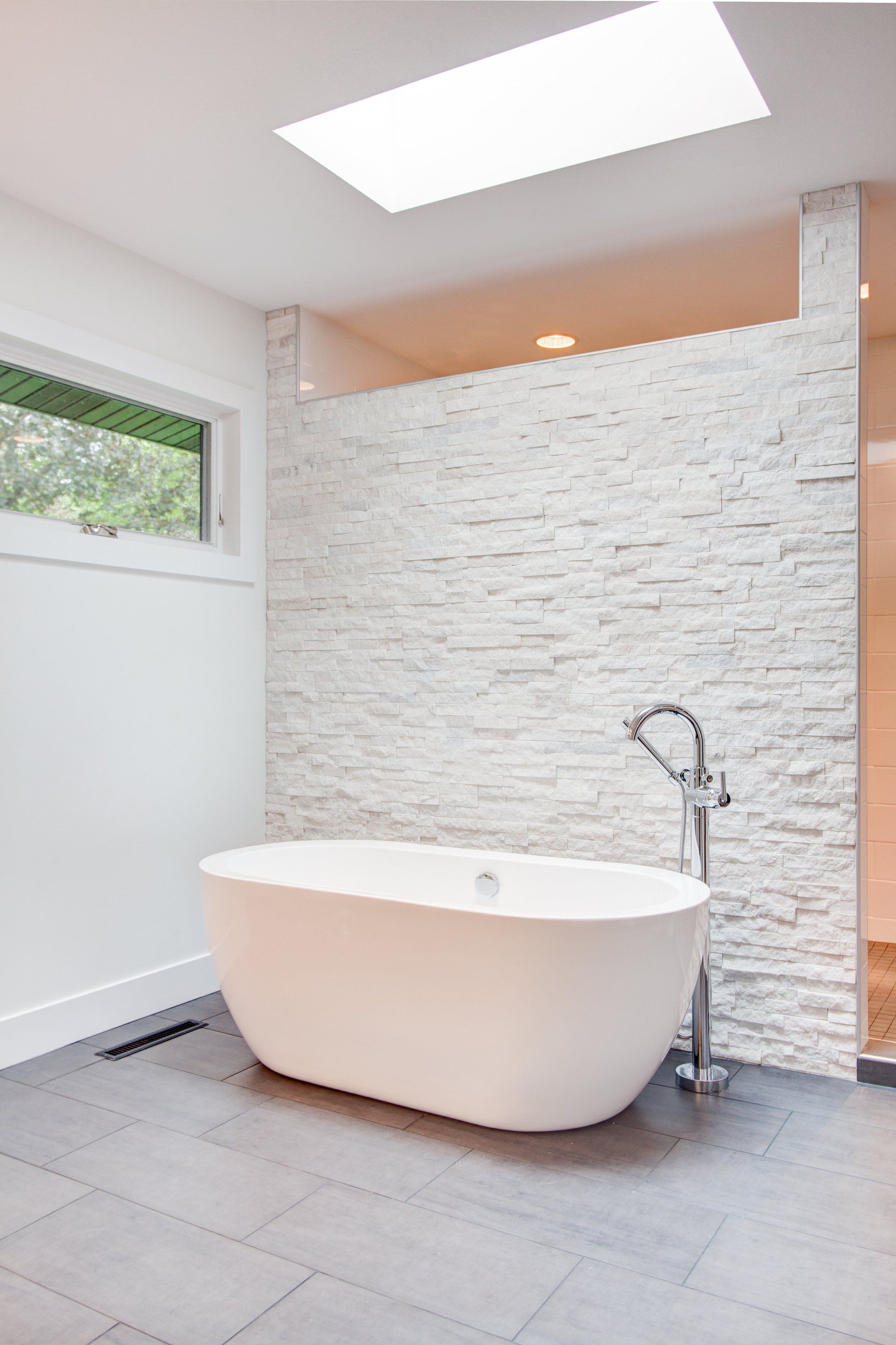 There is a bathtub in the bathroom with a skylight above it.