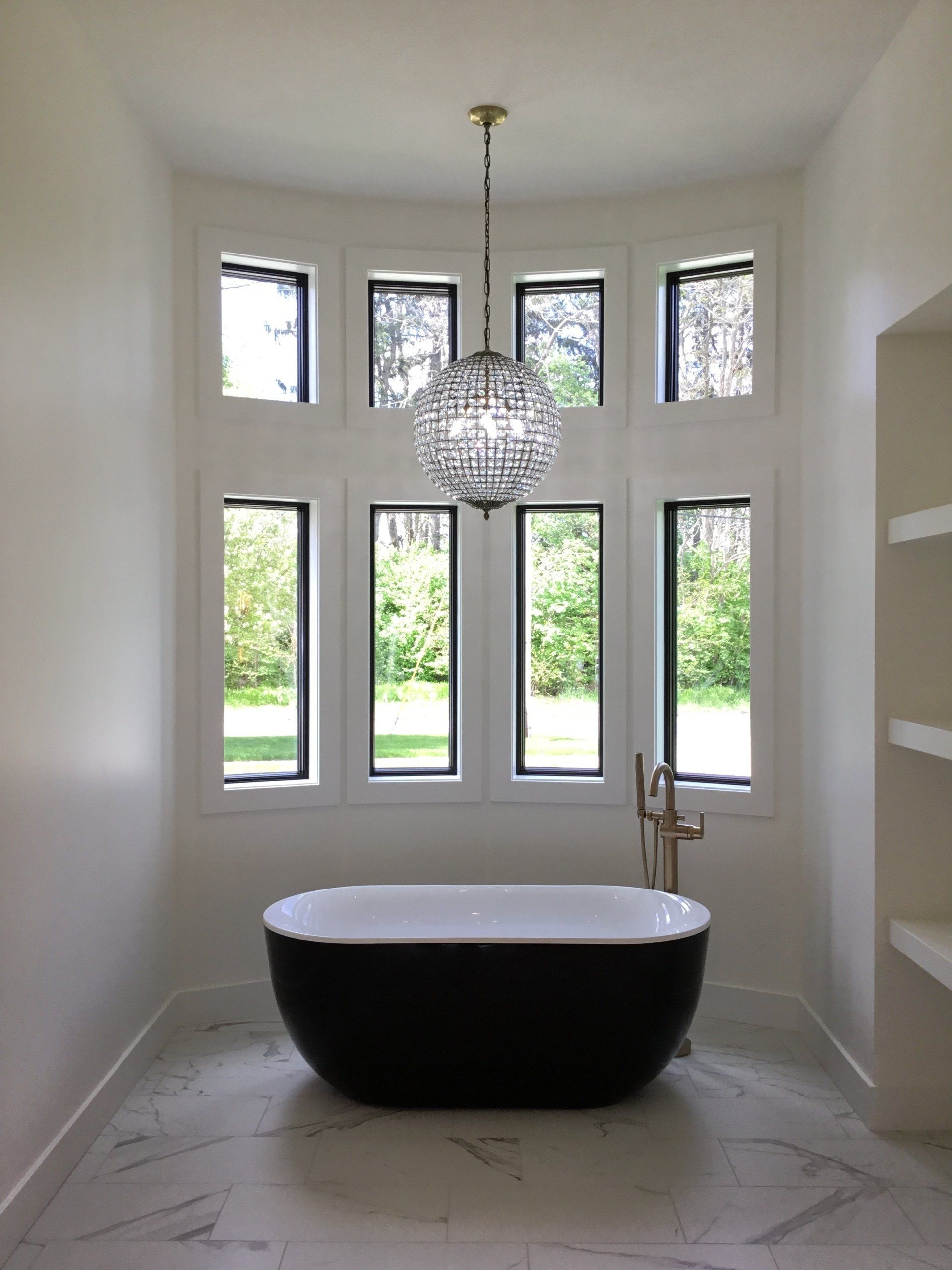 A bathroom with a black tub and a chandelier hanging from the ceiling