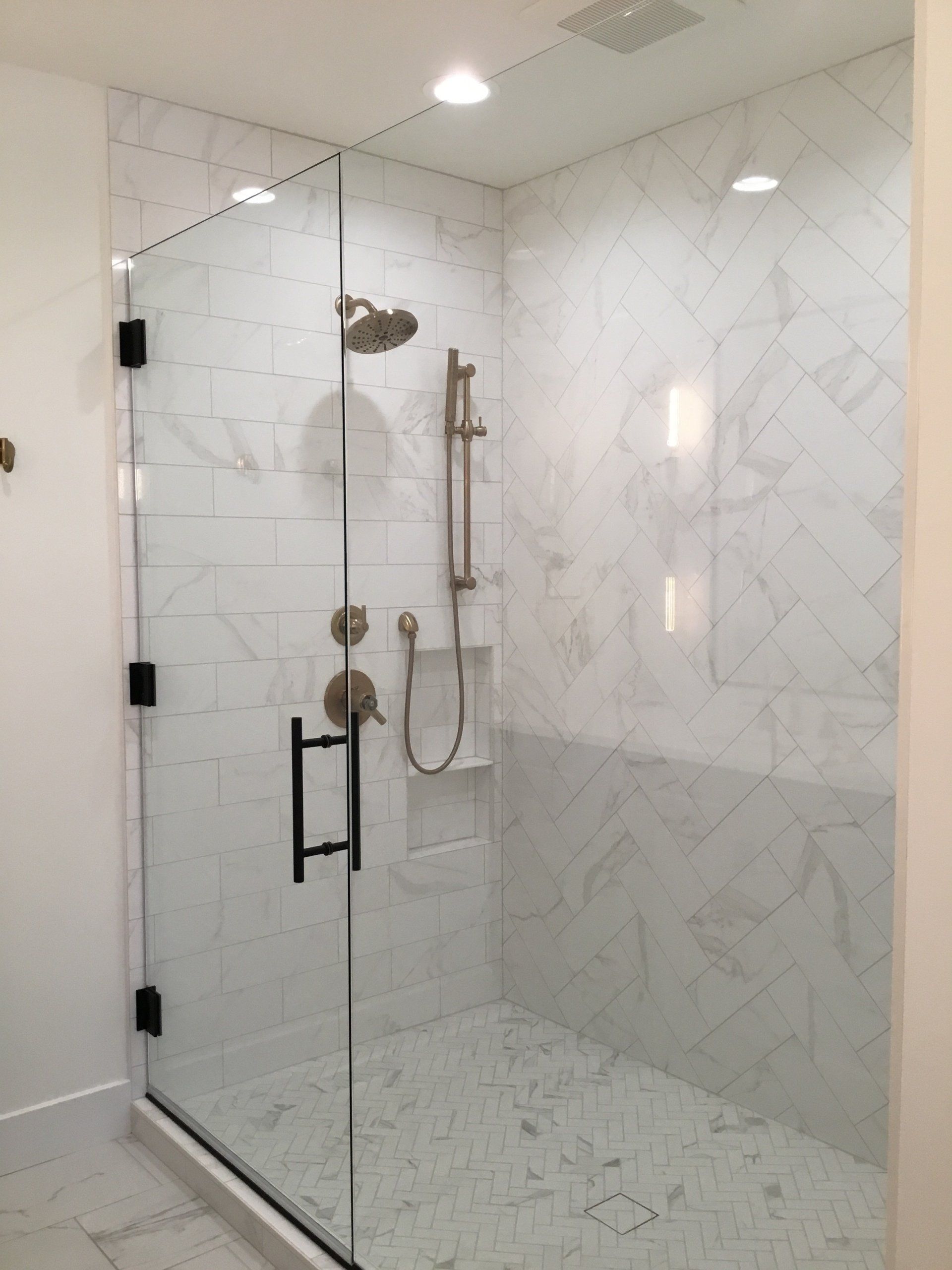 A bathroom with a walk in shower with a glass door