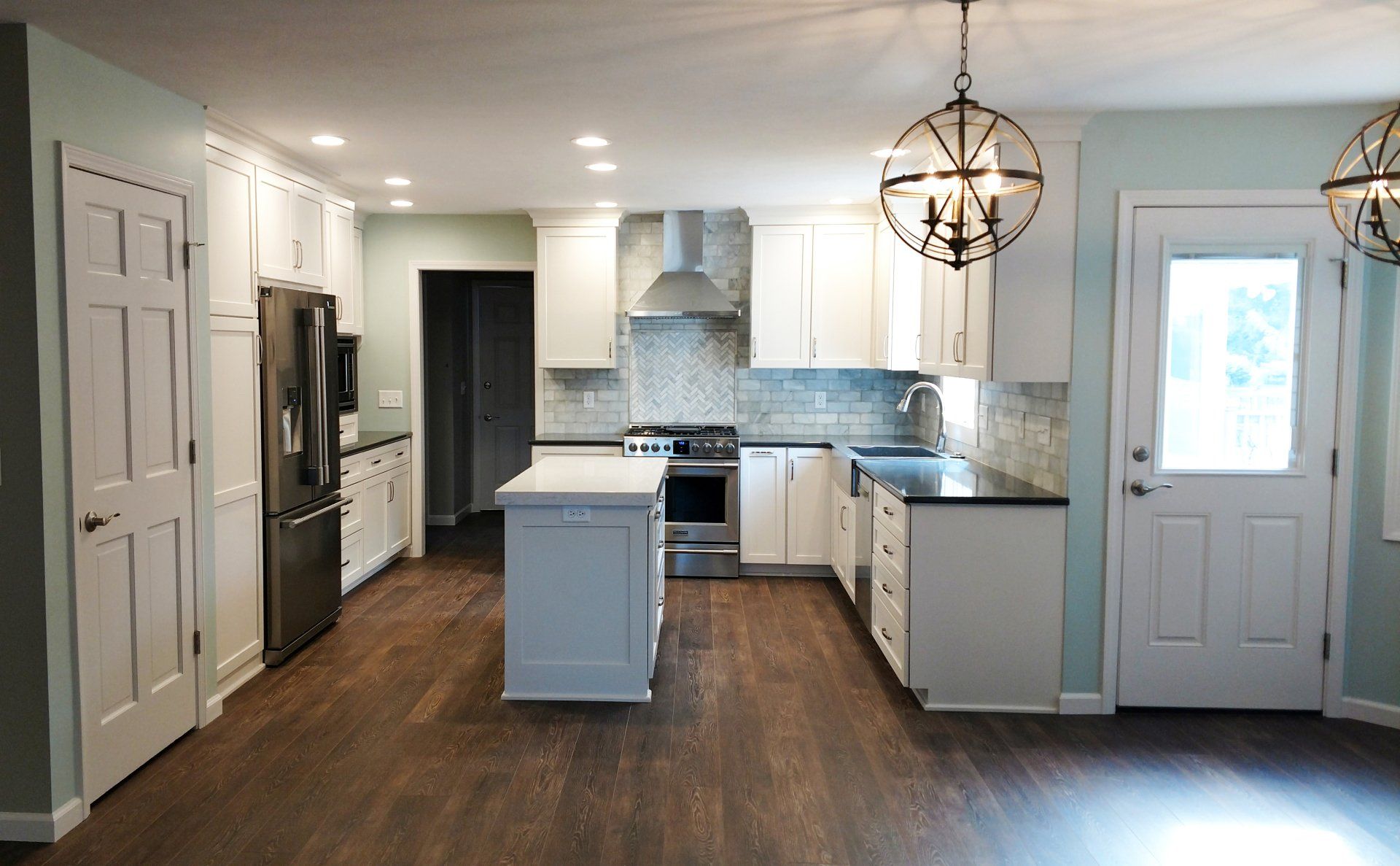 A kitchen with white cabinets , stainless steel appliances , and a large island.
