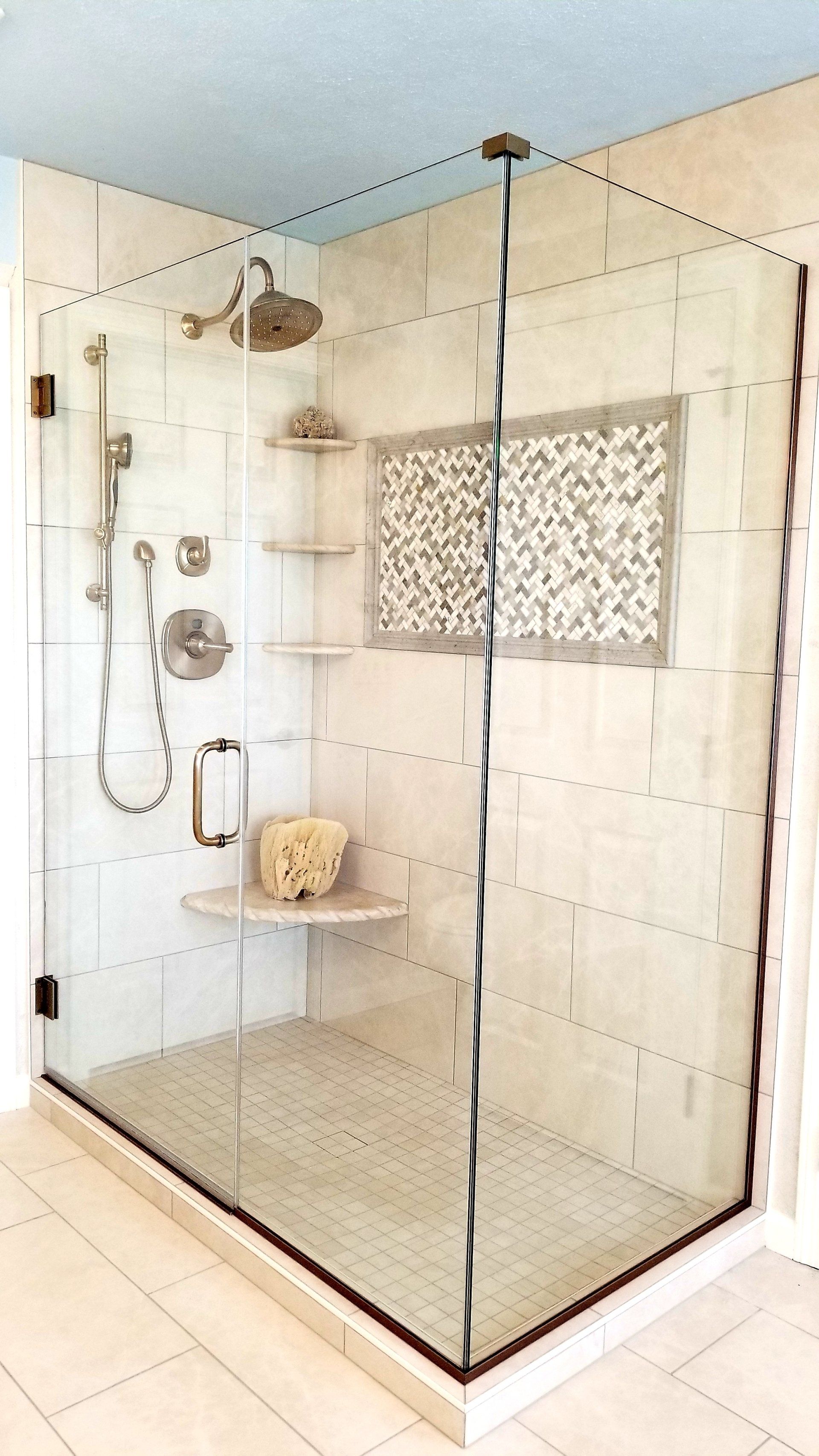 A bathroom with a walk in shower with a glass door.
