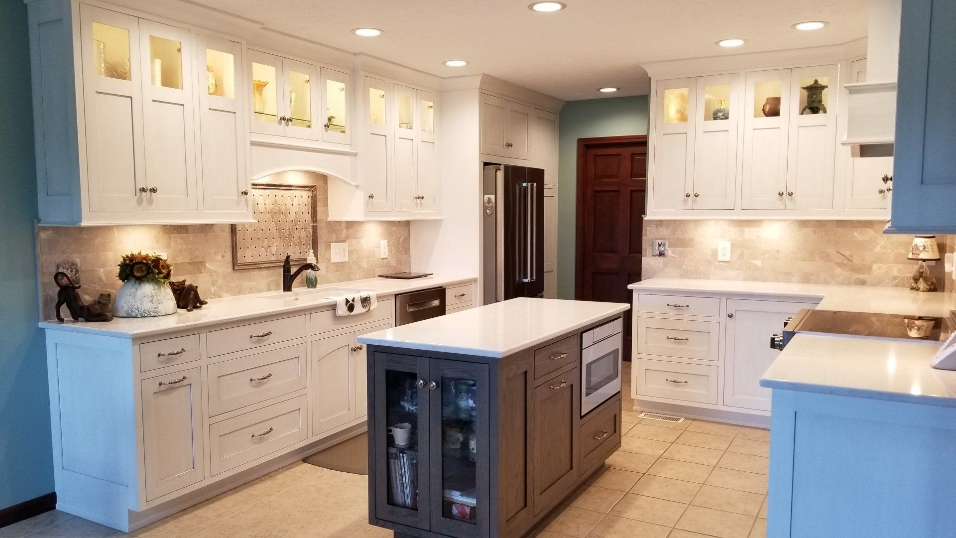 A kitchen with white cabinets and a large island in the middle.