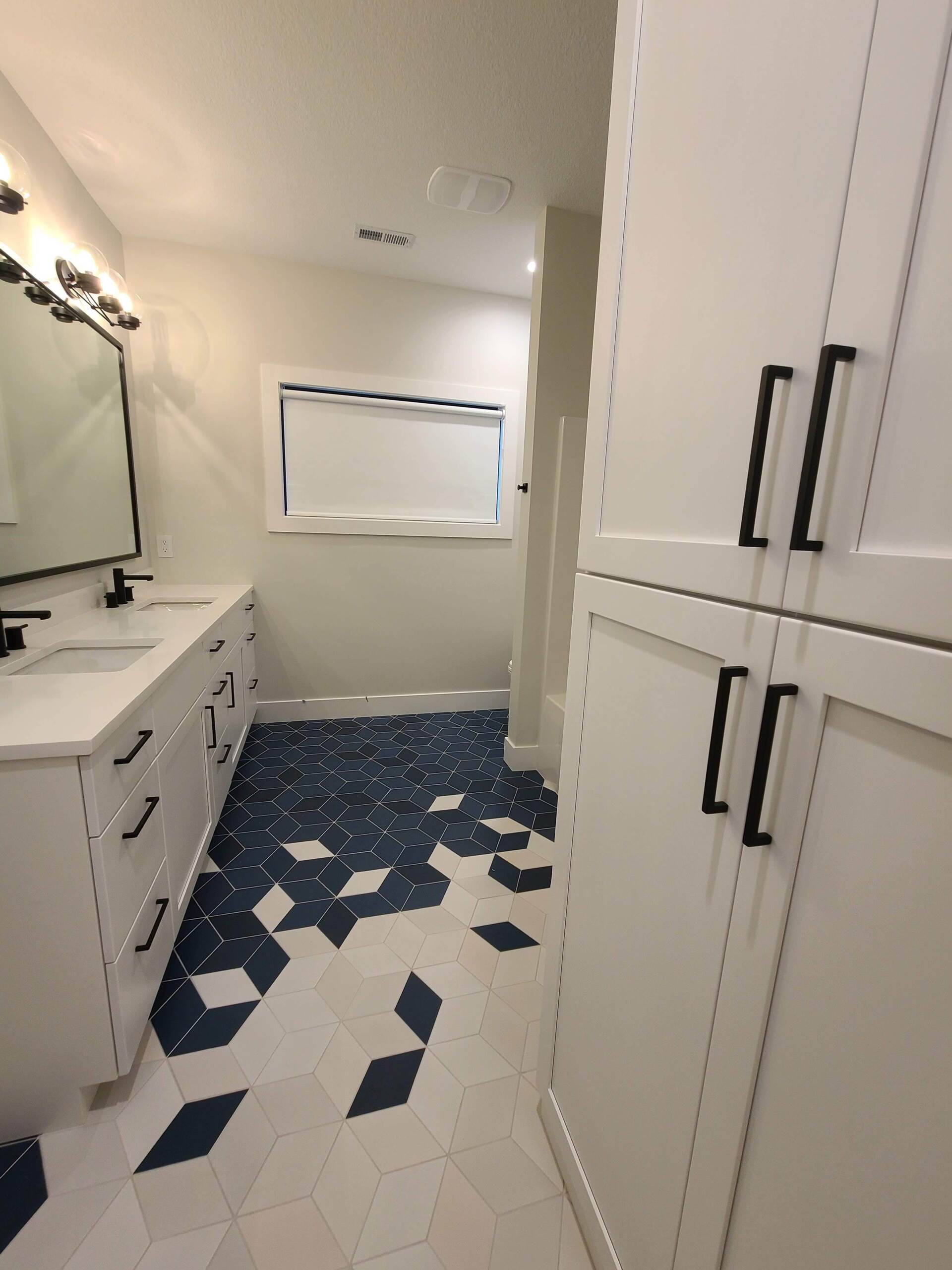 A bathroom with a blue and white tile floor and white cabinets
