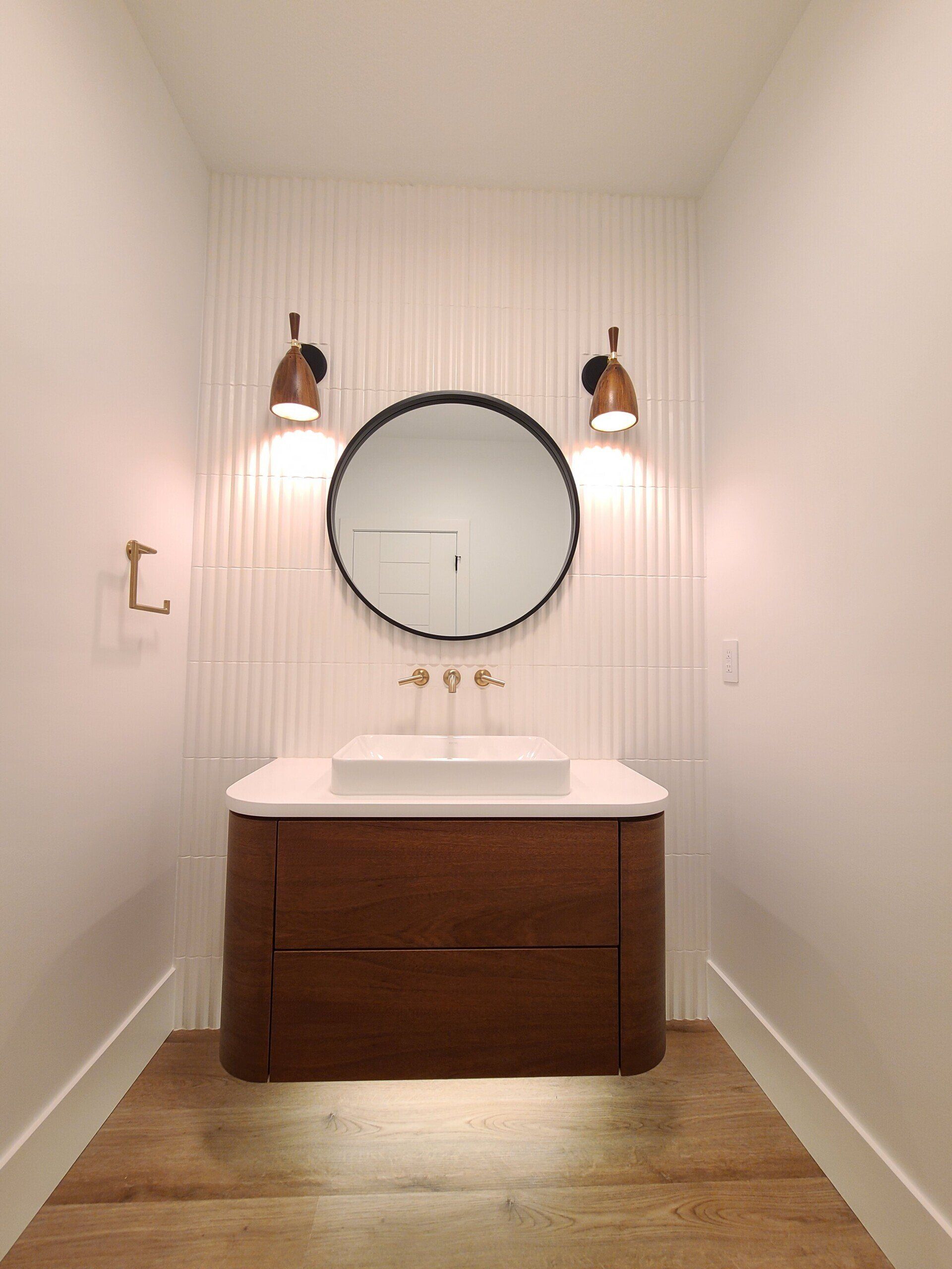 A bathroom with a sink and a round mirror