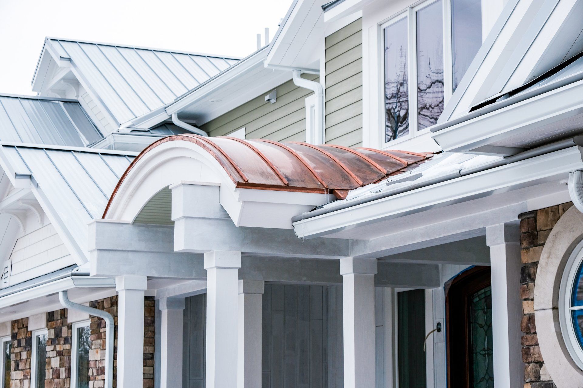 A white house with a copper roof and gutters