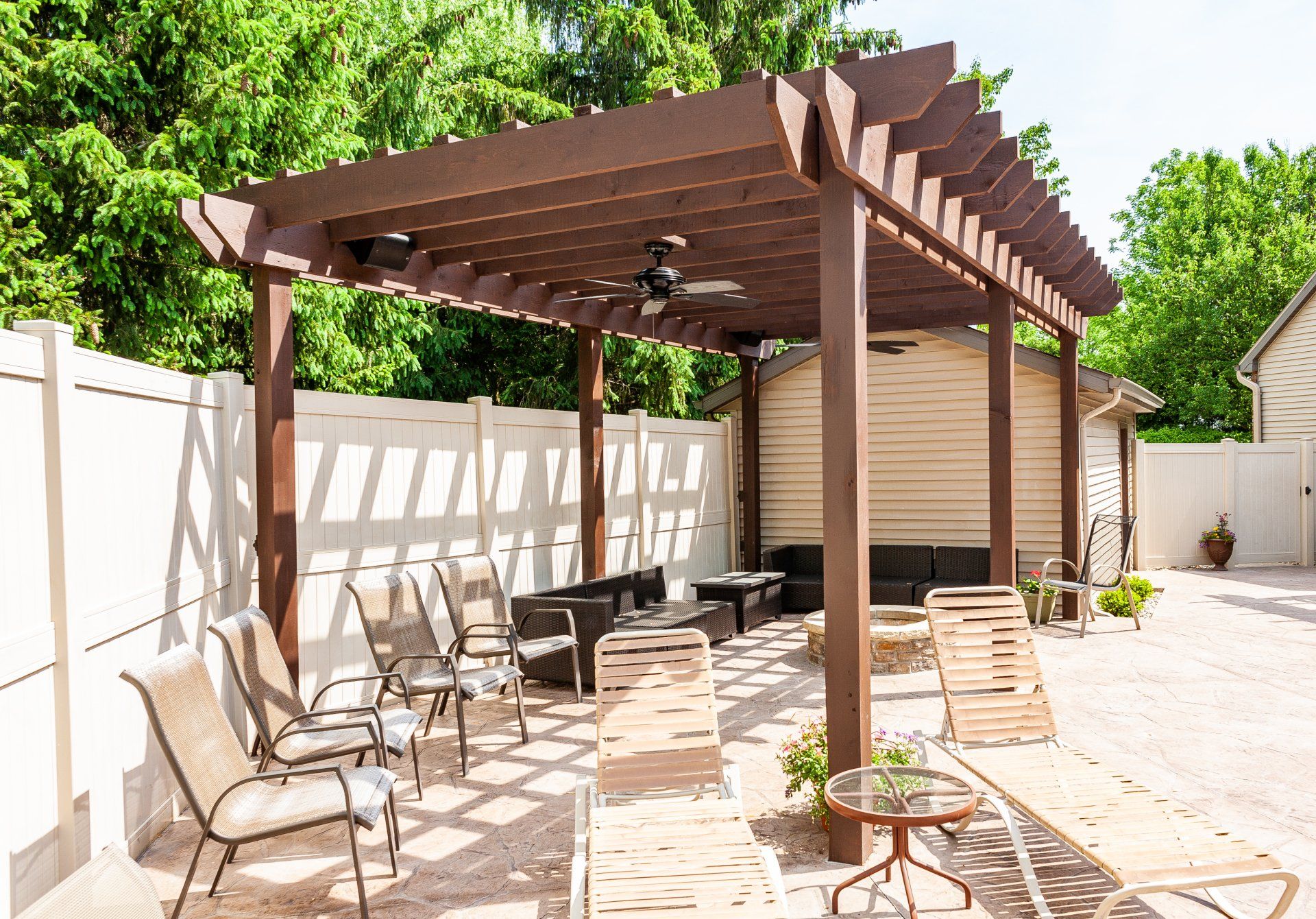 There is a pergola in the backyard with a lot of furniture underneath it.