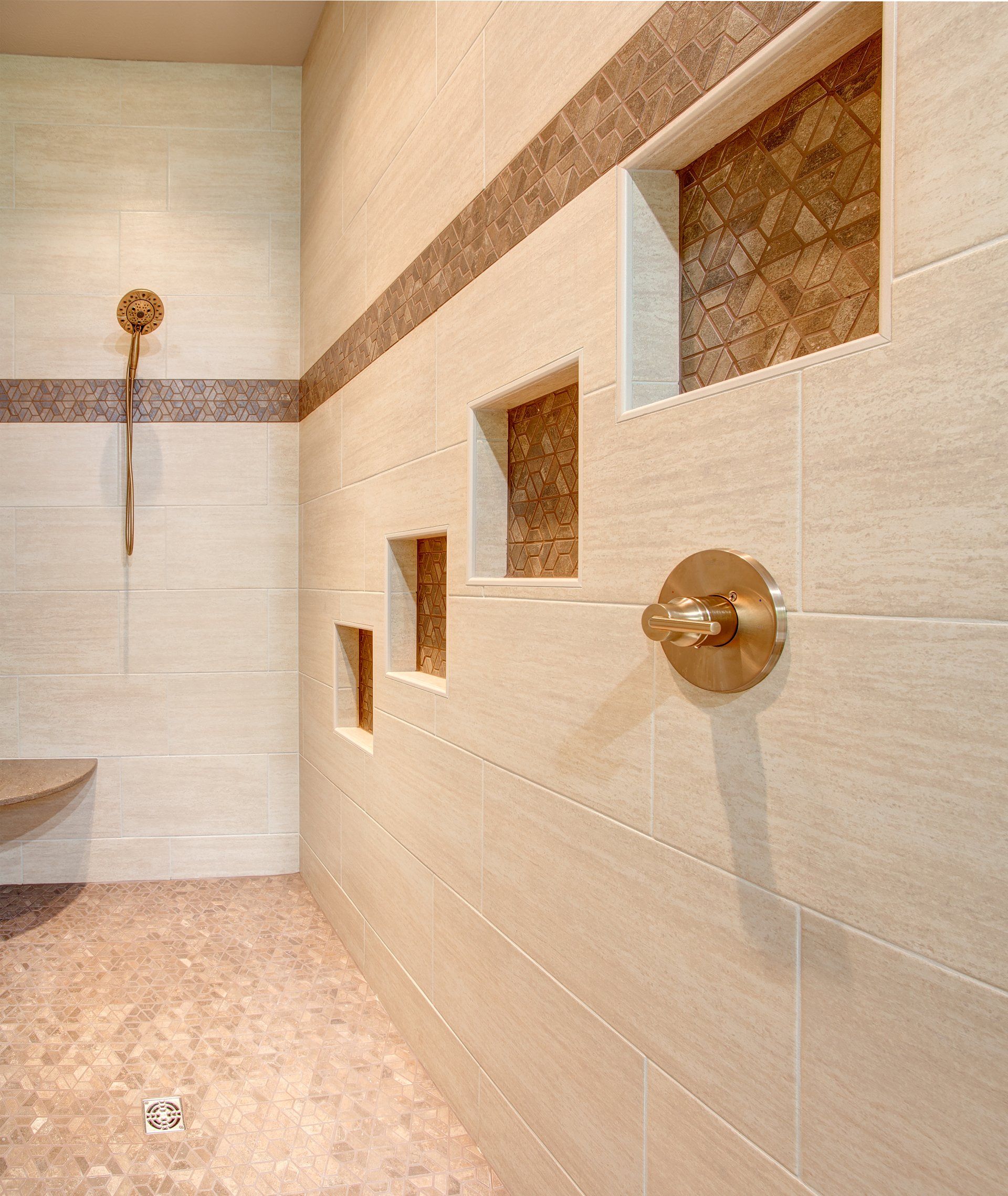 A bathroom with tiled walls and a brass shower head