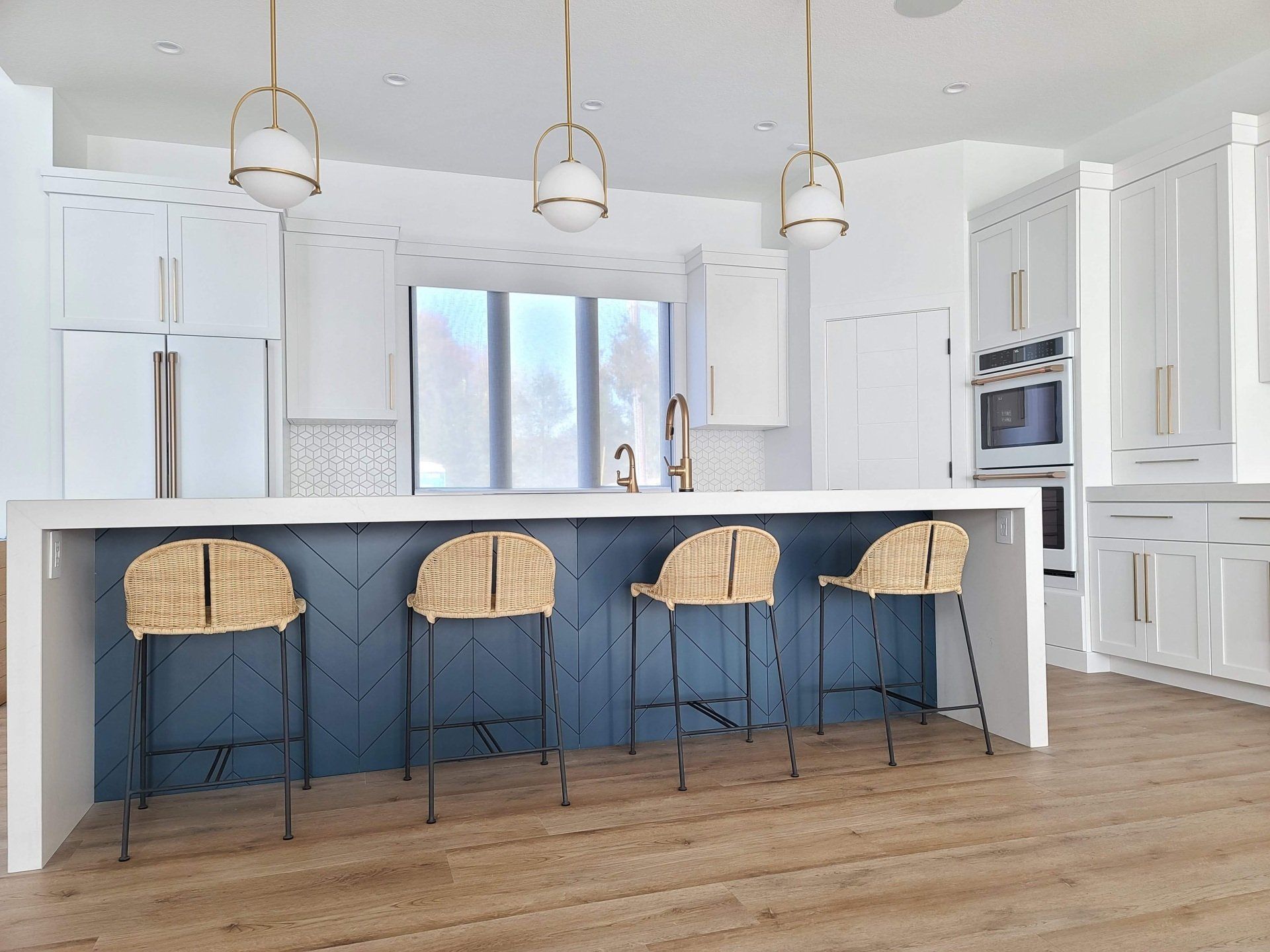 A kitchen with a large island and wicker bar stools.