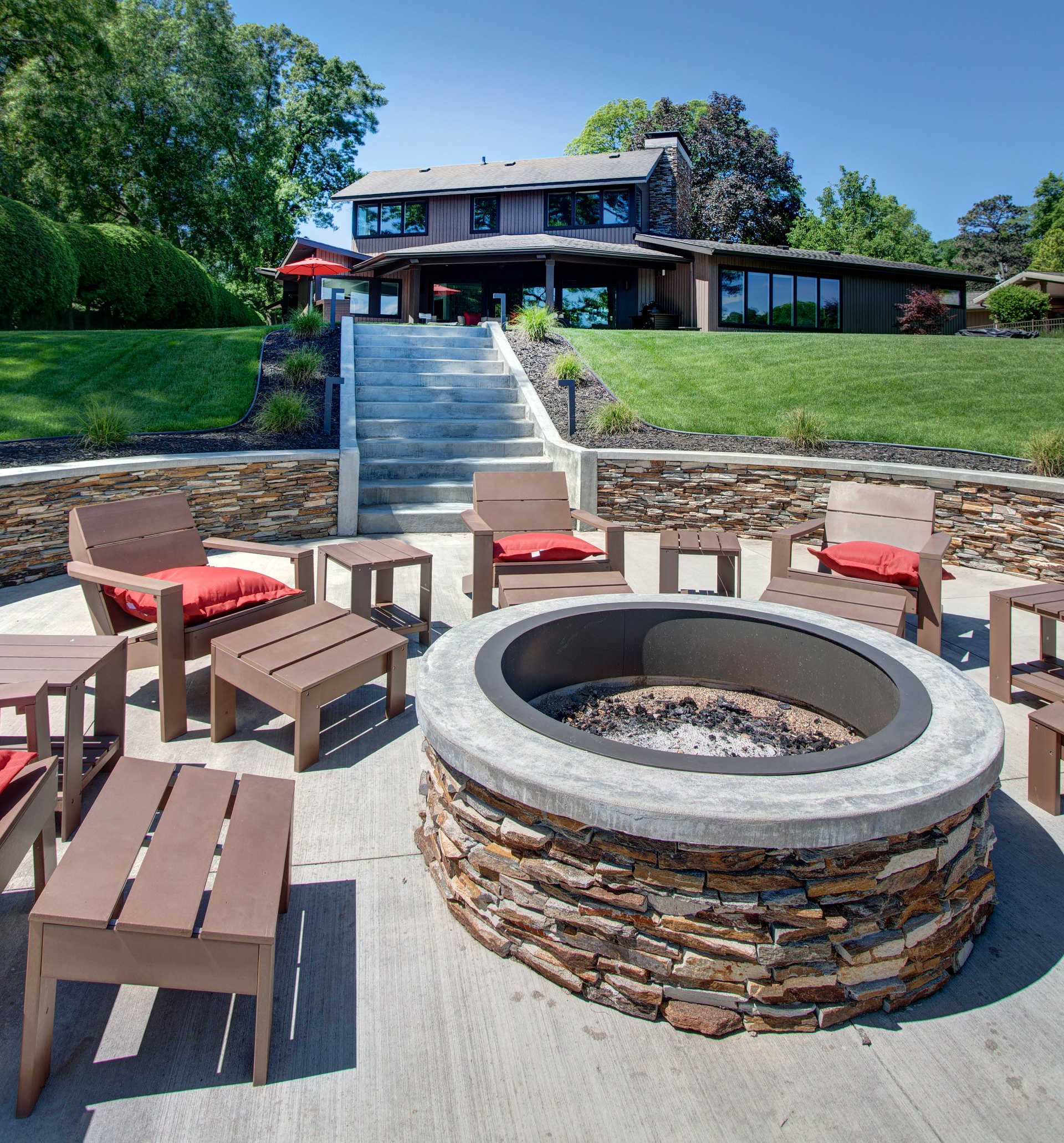 A fire pit surrounded by chairs and tables in front of a house