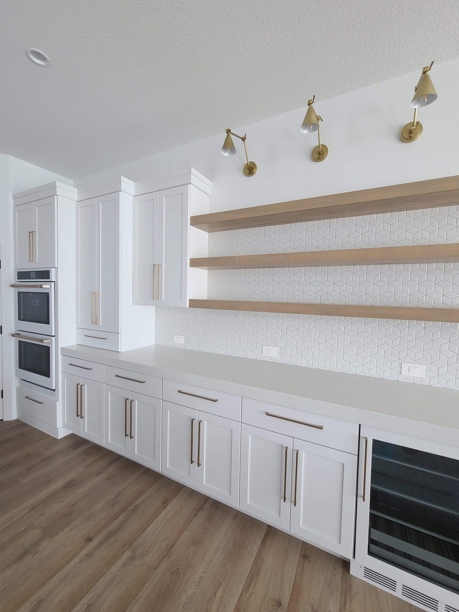 A kitchen with white cabinets and wooden floors