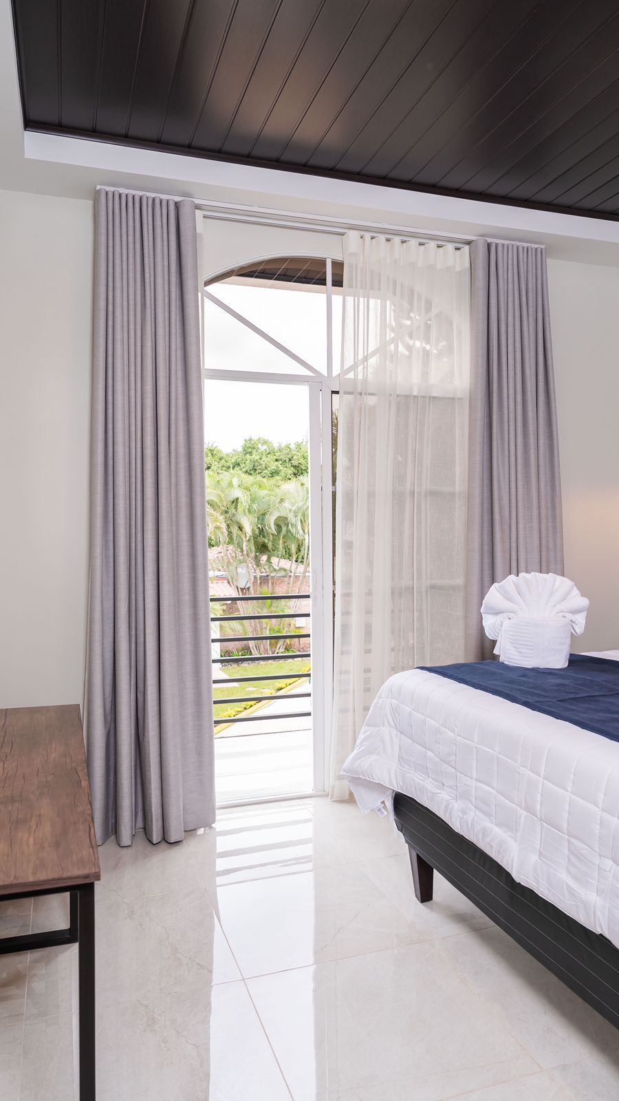 Un dormitorio con cama, silla, alfombra y plantas.