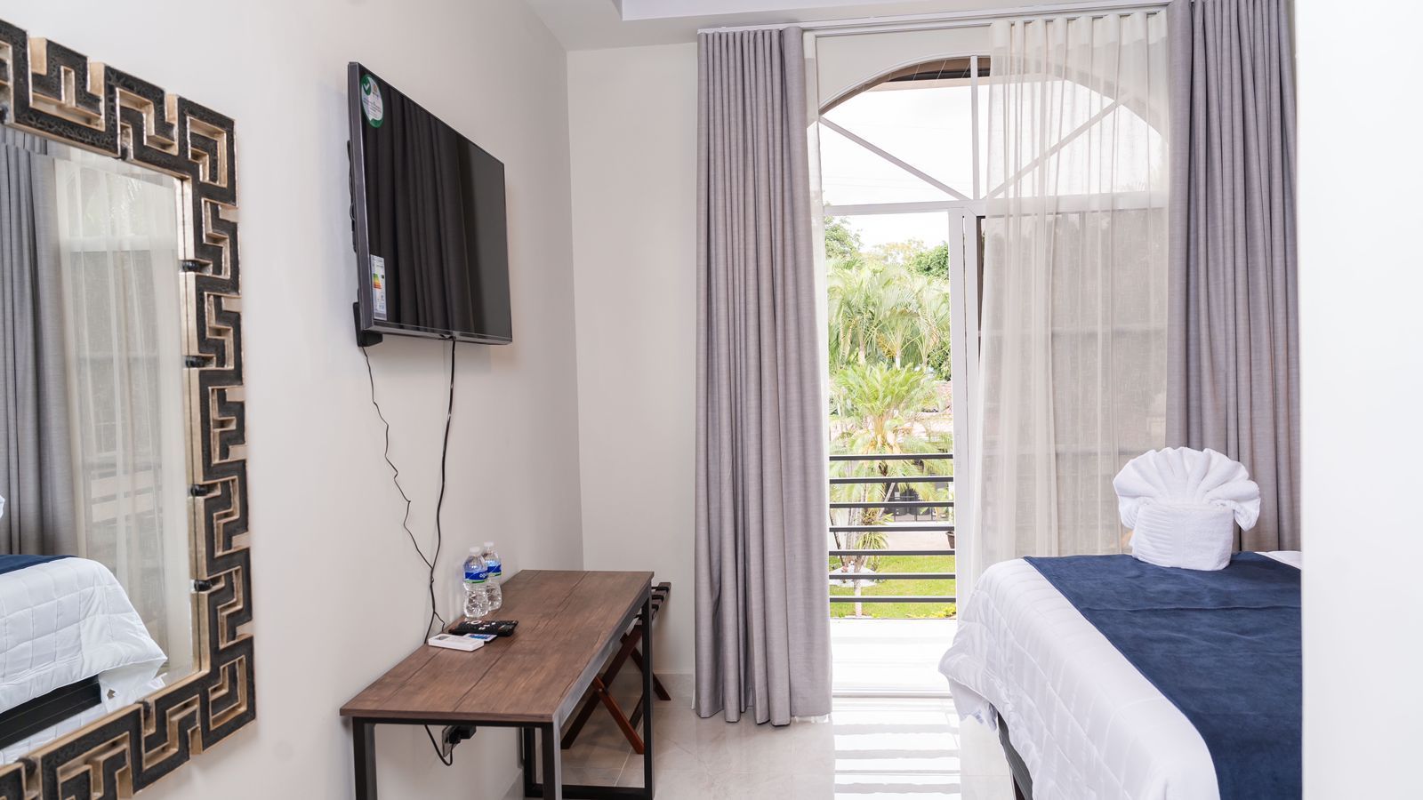 Un dormitorio con cama, escritorio, silla y televisión.