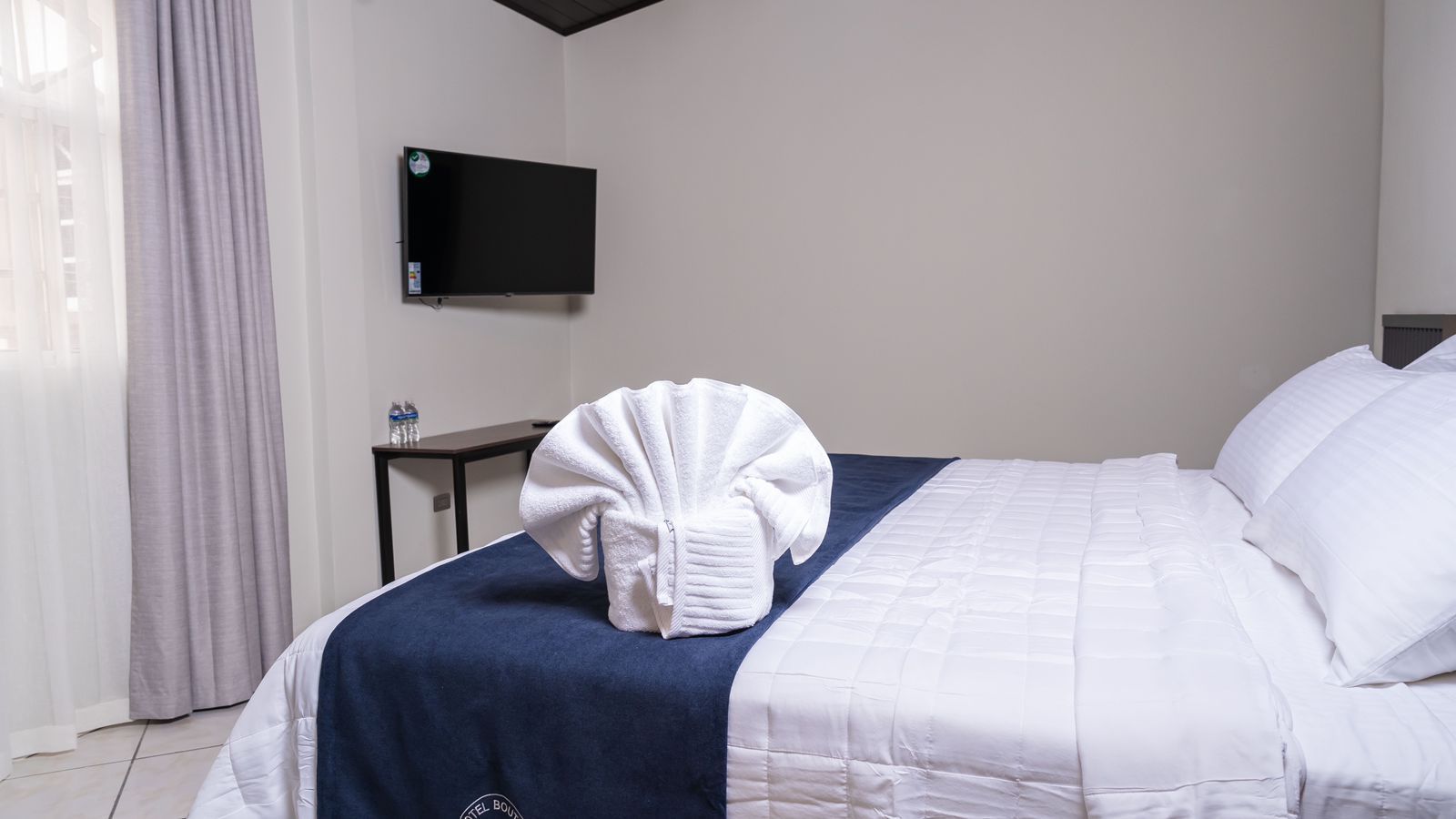 Un dormitorio con cama, escritorio, silla y televisión.