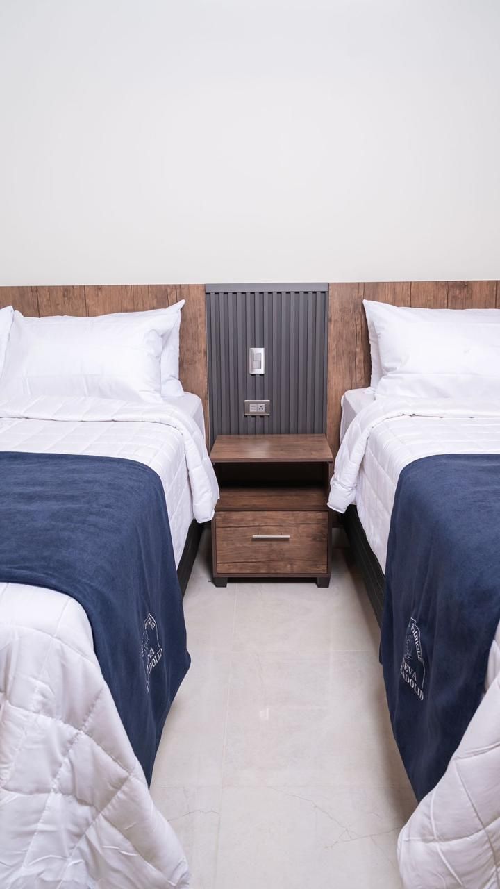 Un dormitorio con cama, escritorio, mesita de noche y televisión.