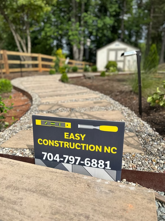 Sign for Easy Construction NC in front of a stone walkway leading to a shed.
