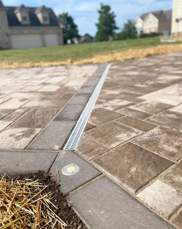 Brick patio with a drainage channel and recessed lighting.