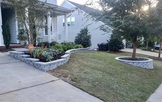 House exterior with a gray retaining wall, landscaping, and a lawn.