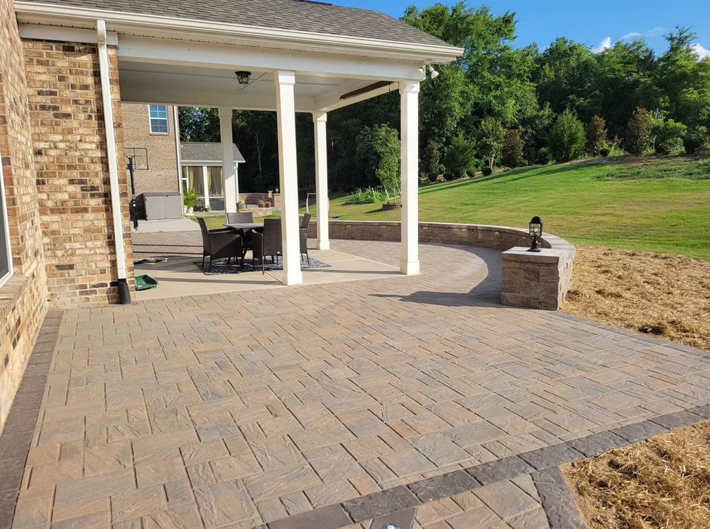 Brick patio with covered outdoor seating and grassy yard in background.
