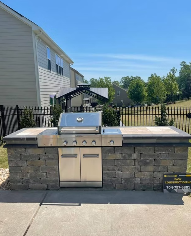 Outdoor built-in grill with stainless steel features, brick facade, and stone countertop on a patio.