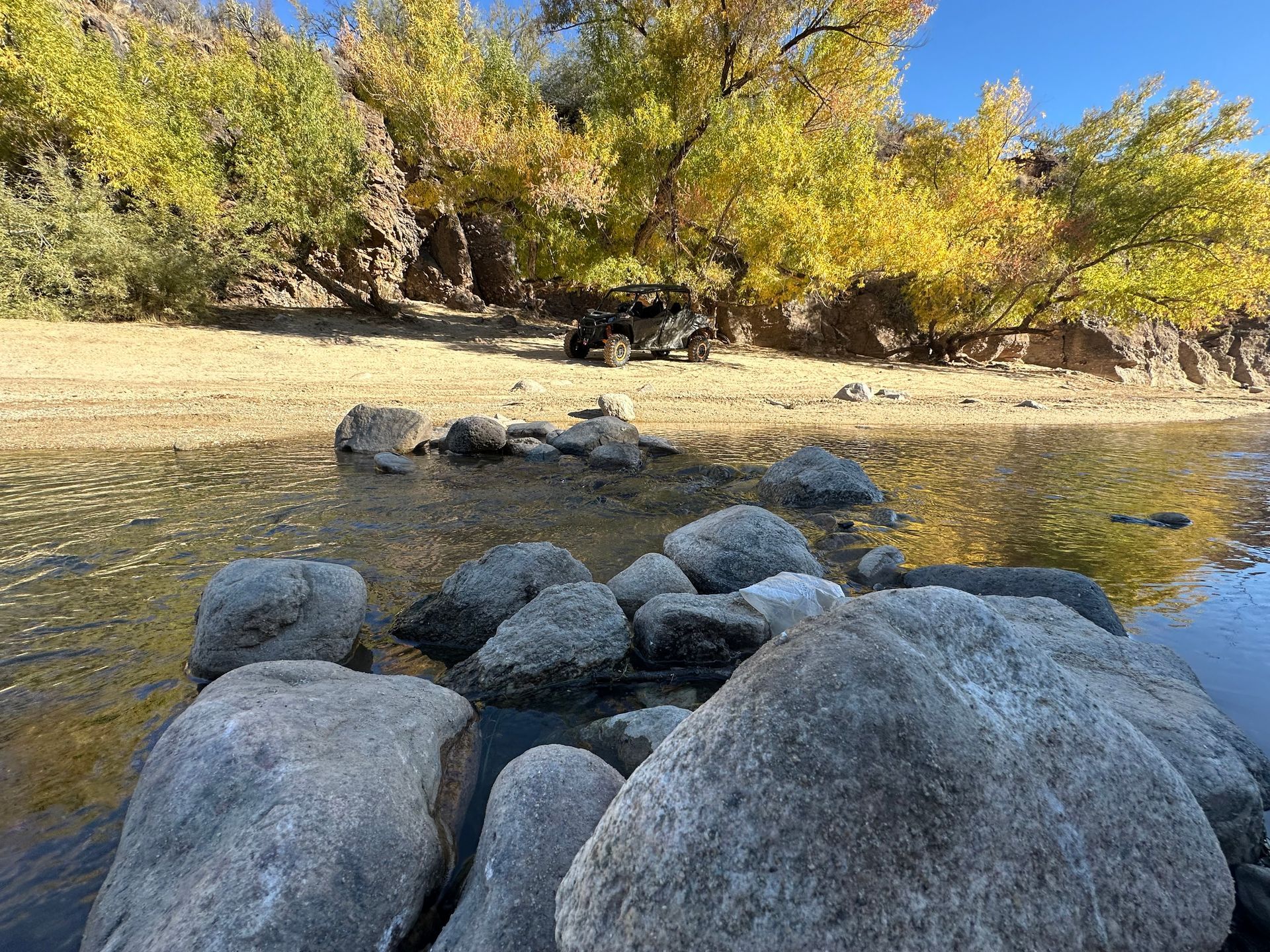 A river with rocks on the shore and trees in the background.
