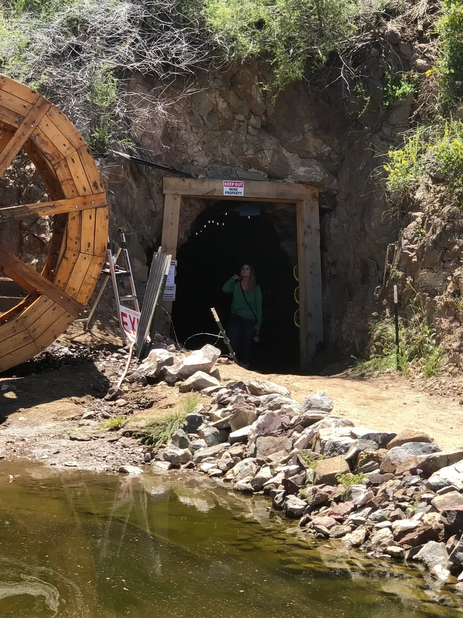 A man is standing in front of a tunnel next to a river.