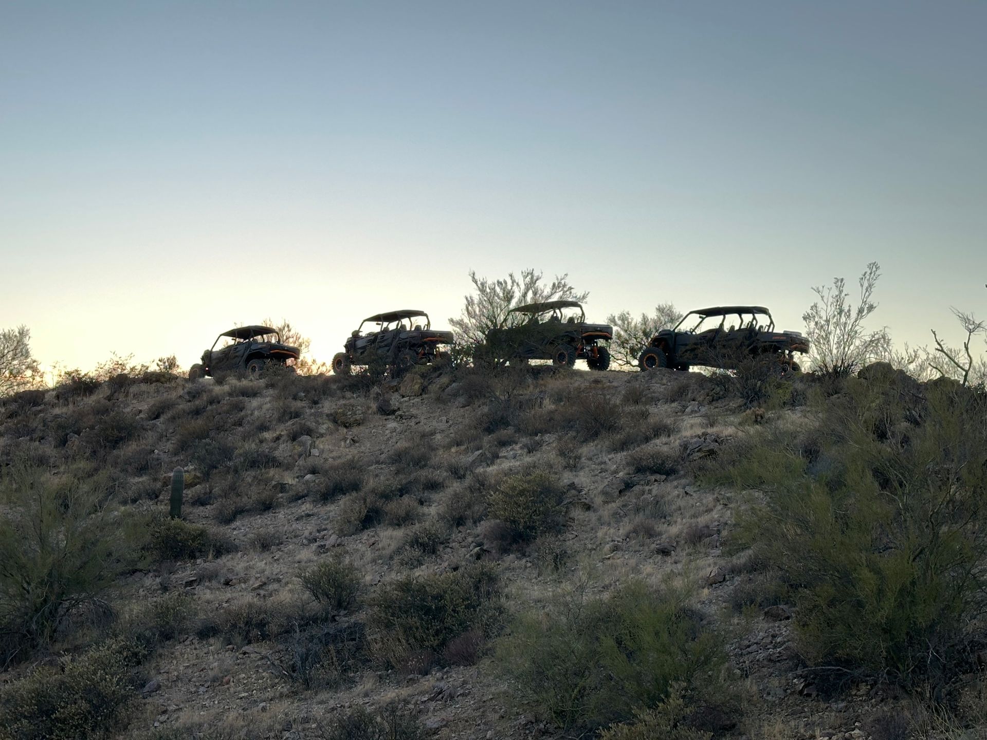 Three atvs are parked on top of a hill in the desert.