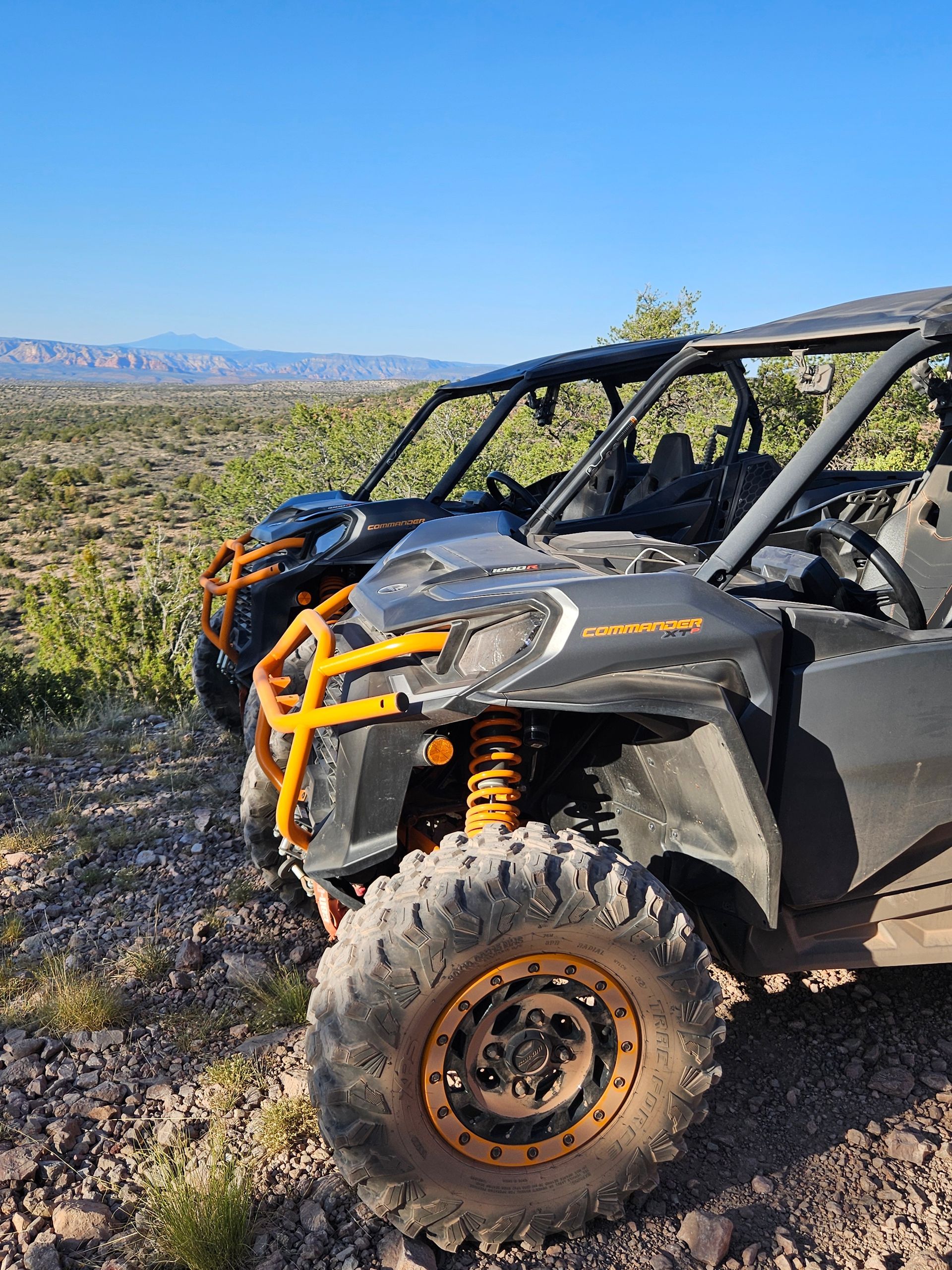 A group of people are driving down a dirt road next to a river.