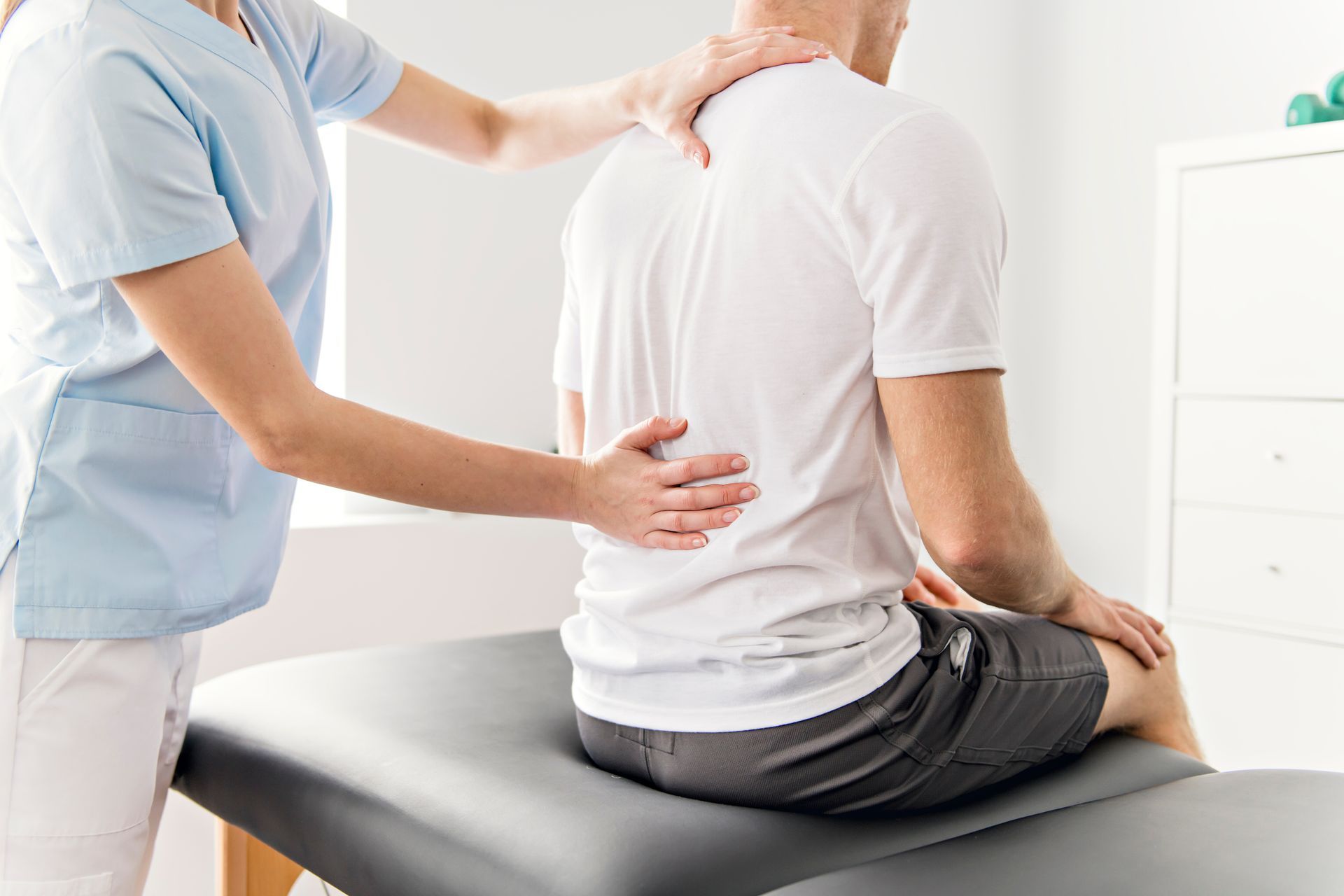 A person receiving physical therapy; therapist's hands on patient's back.
