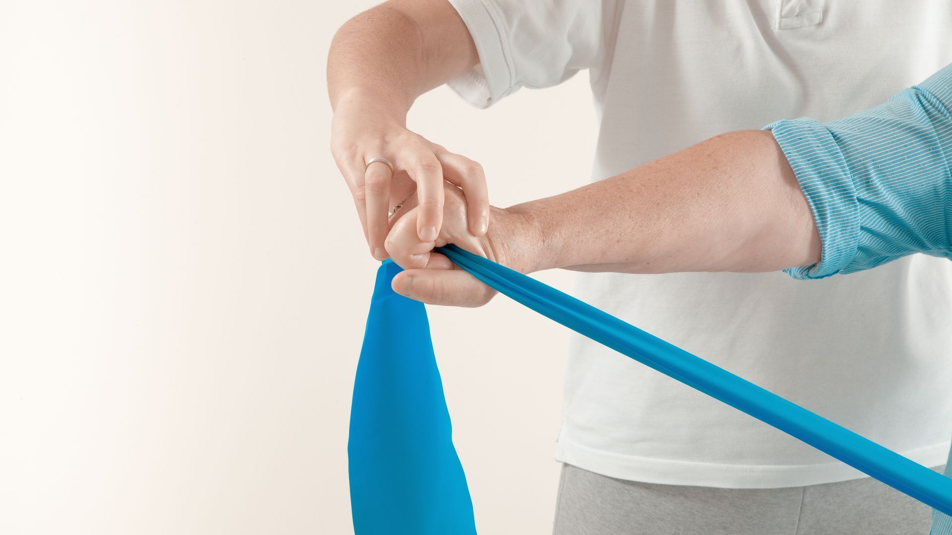 Person with blue exercise band, hands wrapping and holding it.