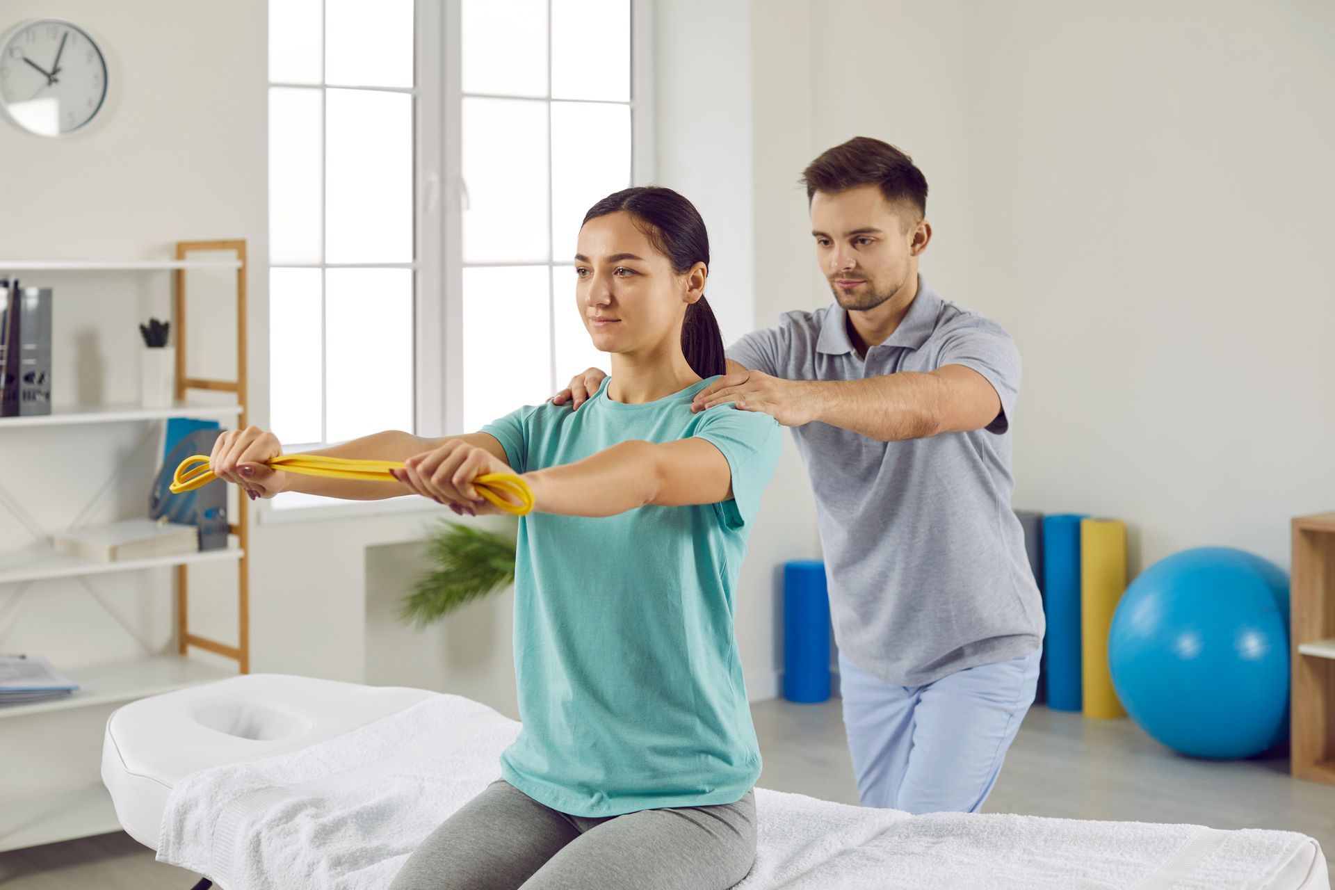 Woman performing physical therapy exercise with assistance from a therapist in a medical office.