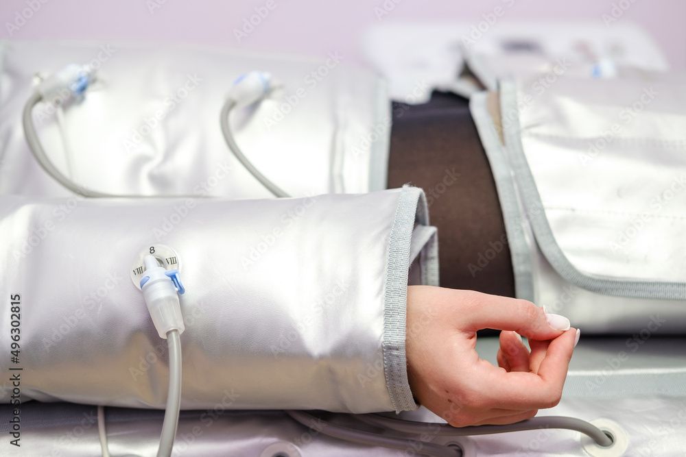 Person's arm inside a compression therapy sleeve connected to a machine.